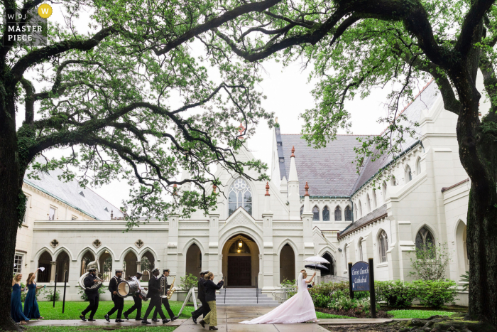 A wedding photojournalist in New Orelans captured this moment at Maison Perrier of A wedding party celebrating with a second line on a rainy day