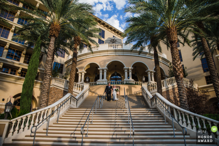 This Nevada wedding photojournalism picture is a first rate example of what candid, nontraditional Henderson wedding photography looks like, as the bride's father walks her down the stairs to her outdoor ceremony at Green Valley Ranch and Spa 