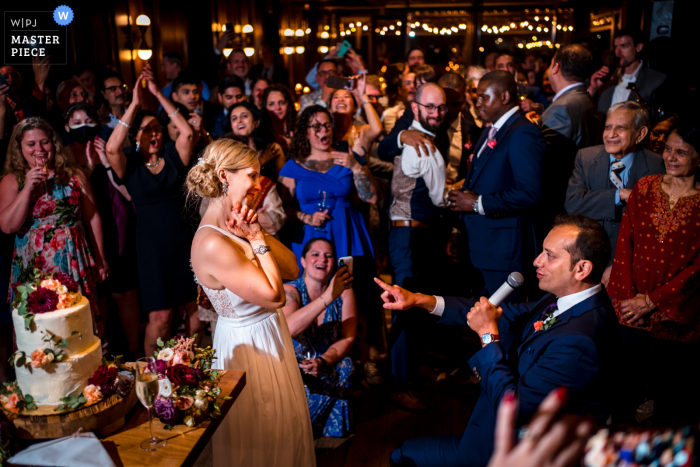 Een trouwfoto in documentairestijl in Washington DC bij de District Winery waarop een moment te zien is waarop de bruidegom zijn bruid een serenade brengt tijdens de receptie