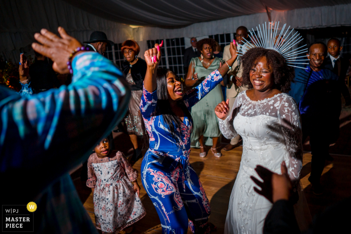 Una imagen de boda al estilo documental de Oxon Hill Manor que muestra un momento de la novia bailando en su recepción con una corona con cierre de cremallera