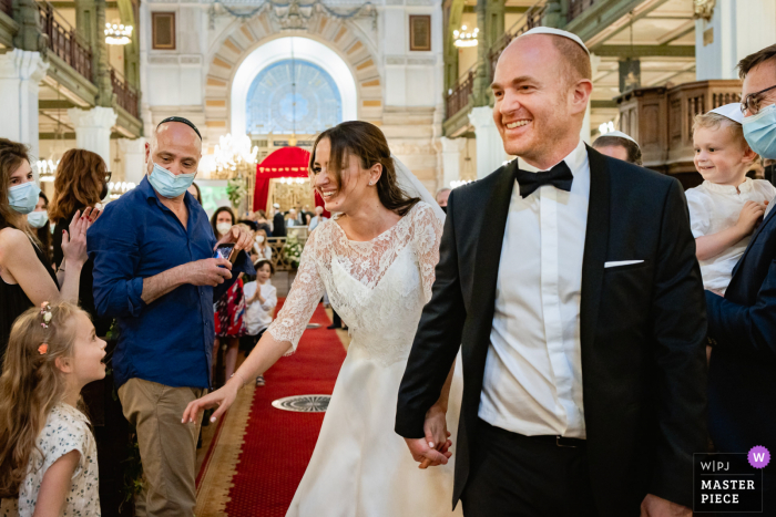 Ein dokumentarischer Hochzeitsfotograf in Paris hat dieses Bild aufgenommen, das Braut und Bräutigam glücklich nach der Zeremonie zeigt