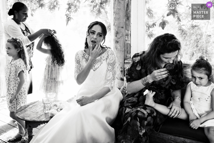 A top documentary wedding photographer from Paris created this image in BW from the Reception venue showing the Bride with children during reception