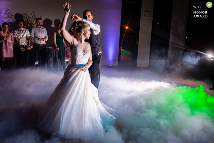 An extraordinary Alsace wedding picture by a pro France photographer showing the bride and groom during the first dance on a bed of dj fog