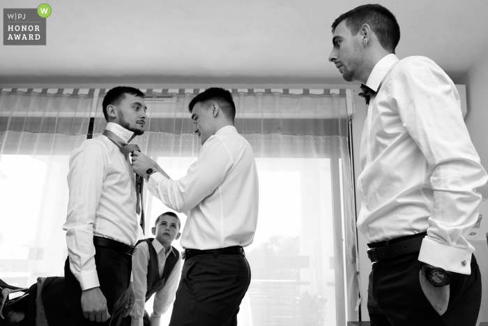 An extraordinary Toulouse wedding image by a professional France photographer conveying the guys getting dressed and fixing ties in BW tones