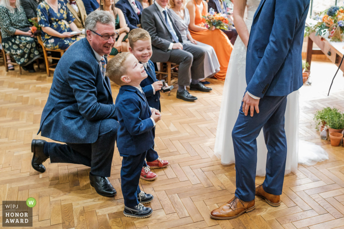 Un'eccezionale immagine del matrimonio di Owlerton, nel Nottinghamshire, di un fotografo professionista del Regno Unito alla Pumping House che mostra i nipoti degli sposi e suo padre che presentano gli anelli alla coppia durante la cerimonia di matrimonio