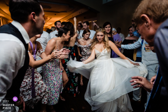 Best Philadelphia documentary wedding photojournalism image showing the bride living her best life on the dance floor and Being framed by the groom and her uncle in the foreground Best Philadelphia documentary wedding photojournalism image showing the bride living her best life on the dance floor and Being framed by the groom and her uncle in the foreground