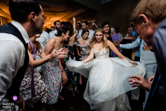 Melhor imagem de fotojornalismo de casamento documental da Filadélfia mostrando a noiva vivendo sua melhor vida na pista de dança e sendo emoldurada pelo noivo e seu tio em primeiro plano