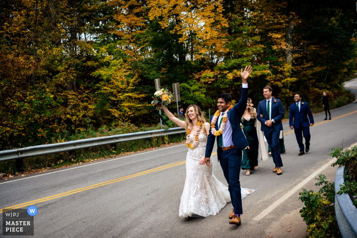 Ein Spitzenbild aus Jackson, NH, gehört zu den besten Hochzeitsfotografien im Whitneys Inn und zeigt die Braut und den Bräutigam, die winken, nachdem sie die Zeremonie verlassen und die Straße zum Empfangsort überquert haben Ein Spitzenbild aus Jackson, NH, gehört zu den besten Hochzeitsfotografien im Whitney's Inn und zeigt die Braut und den Bräutigam, die winken, nachdem sie die Zeremonie verlassen und die Straße zum Empfangsort überquert haben