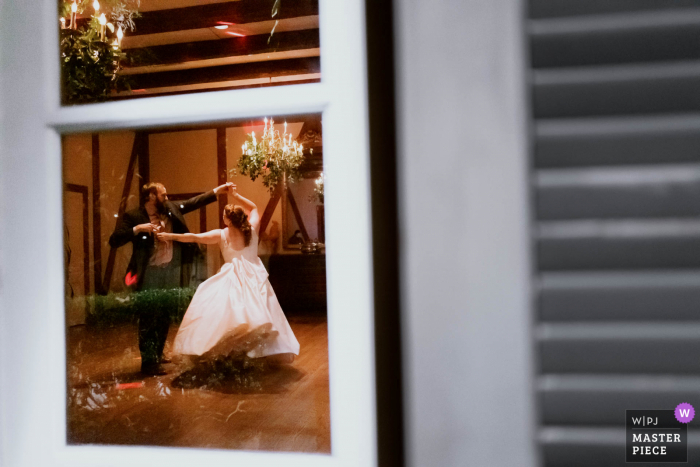 Best San Antonio documentary wedding photojournalism image from Club Giraud in Texas showing a Couple having a fun dance together and photographed through window of reception window