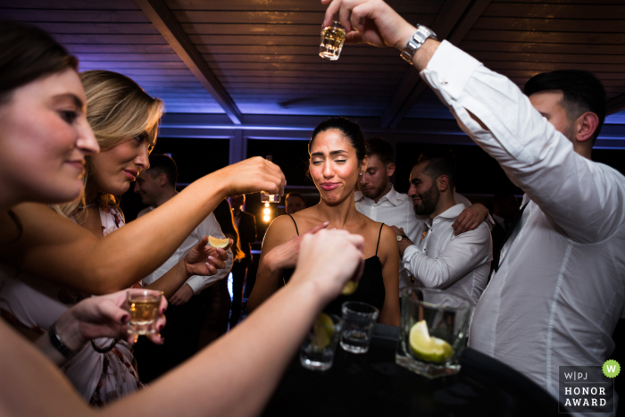 An exceptional Greater Manchester wedding image by a pro UK photographer at Manchester Hall exhibiting guests taking drinking shots on the dance floor at the venue 