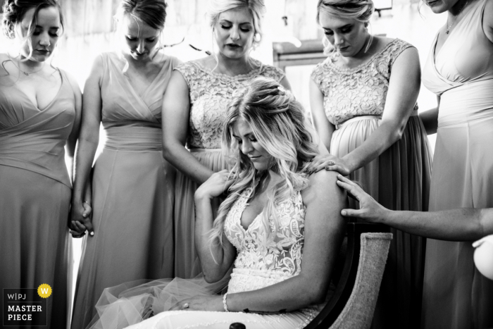 Una foto de boda documental espiritual en blanco y negro de Asheville, NC, que muestra a las damas de honor apoyando a la novia durante una oración antes de la ceremonia