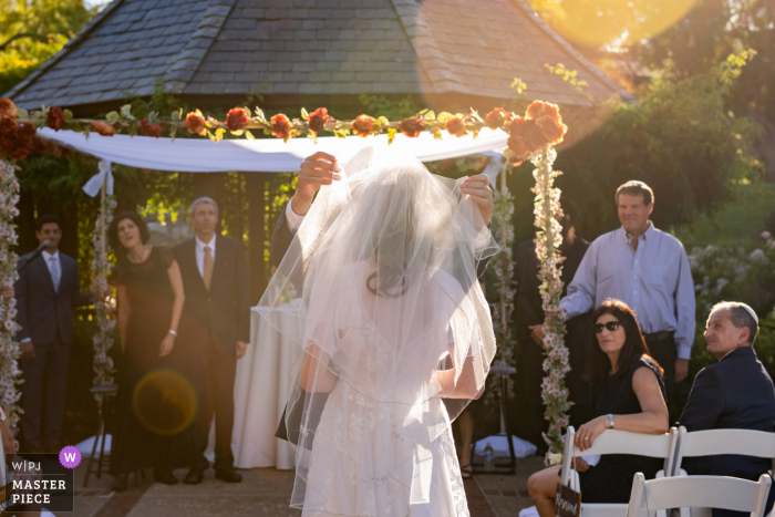 O fotógrafo documental de casamento de Oakland, Califórnia, criou esta imagem enquanto o noivo remove o véu da noiva