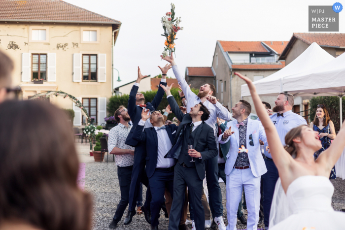 Franse trouwfoto van een locatie in Cuvry tijdens een boeketgooien met de mannen bij de receptie