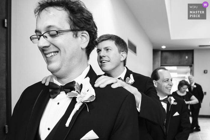 BW documentary wedding photographer at the Holy Trinity Episcopal Church in Decatur, Georgia captured this The best man whispering in the grooms ear as they wait to walk down the aisle