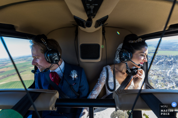 Fotografia documental de casamento em Indre, França, mostrando a noiva e o noivo em um passeio de helicóptero sobre o campo Fotografia documental de casamento em Indre, França, mostrando a noiva e o noivo em um passeio de helicóptero sobre o campo