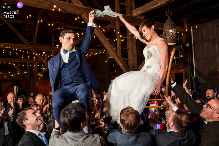 Best Leesburg wedding venue photography at Riverside on the Potomac showing Bride and Groom held up in chairs during Hora