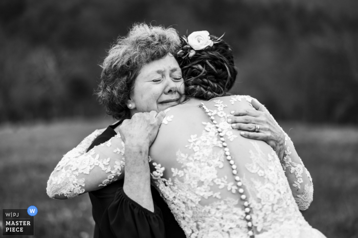 Hochzeits- und Eventfotografie aus Charlottesville im 12 Ridges Vineyard in Virginia von Mom, die die Braut fest umarmt, während sie sich fertig macht