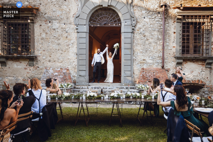 Fotógrafo de casamento documental em um local do evento, Castello di Meleto em Siena capturou a noiva e o noivo chegando à recepção do jantar