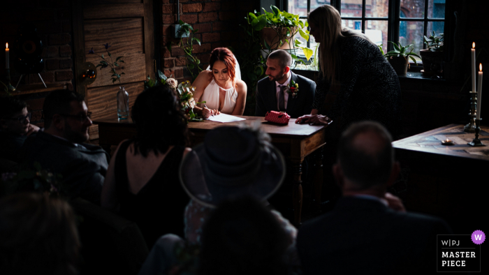 Fotografía del lugar de la boda de Chimney House en Sheffield que muestra a la novia y al novio firmando el registro