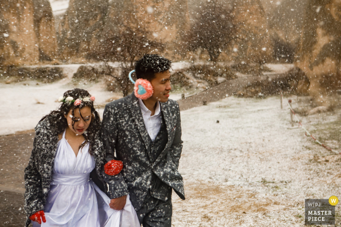 Documentaire trouwfotograaf op een evenementenlocatie in Cappadocië, fotografeerde bruid en bruidegom buiten in de sneeuw op weg naar het Lunar Hotel