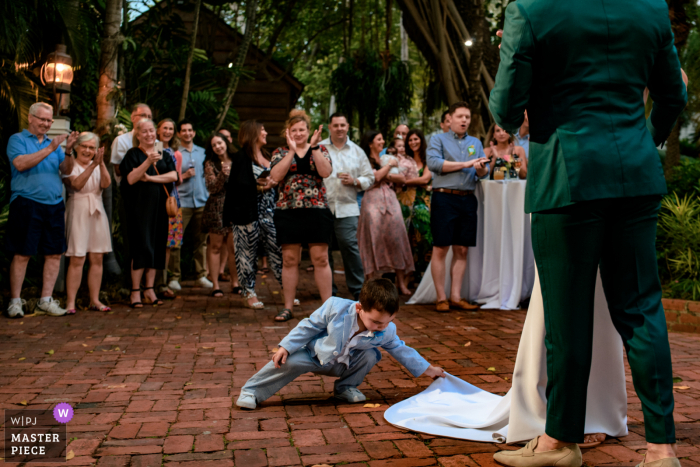 Key West based wedding and event photography in Florida capturing the brides nephew wanted to be like mom and fix the brides dress during first dance