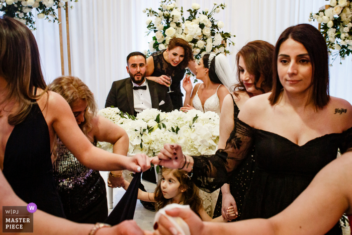 Fotografía del lugar de la boda en Londres en la Regency Banqueting Suite que captura a una pareja descansando en la recepción mientras los invitados bailan Fotografía del lugar de la boda en Londres en la Regency Banqueting Suite que captura a una pareja descansando en la recepción mientras los invitados bailan