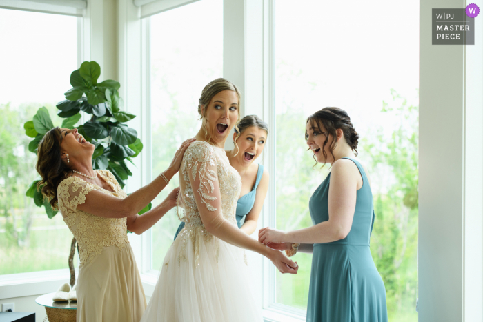 La mejor fotografía del lugar de bodas de Corolla, Carolina del Norte en The Whalehead Club, que muestra expresiones dramáticas mientras la novia se prepara con su madre y sus hermanas