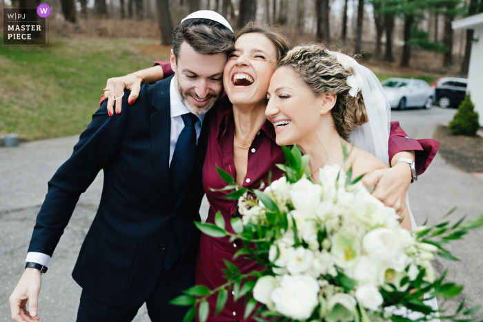 Ein dokumentarischer Hochzeitsfotograf im Veranstaltungsort Pelham House Resort in West Dennis, Cape Cod, MA, hat diese lustige Umarmung nach der Zeremonie festgehalten