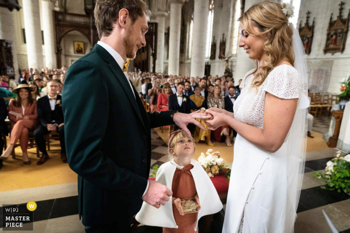 Documentary photography from a wedding venue in France capturing the young girl watching the bride and groom ring exchange