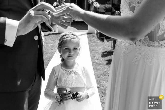 Imagem de casamento Landgoed Wolfslaar de um local ao ar livre em Breda mostrando a dama de honra trazendo os anéis e observando o que seus pais fazem