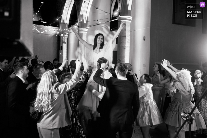 Um fotógrafo de reportagem de casamento do Reino Unido no local do evento The Garden Museum em Londres capturou esta noiva levantada pela multidão