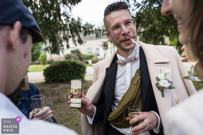 Blois based wedding and event photography in Loir-et-Cher, France of Reception guests showing phone pictures to friends