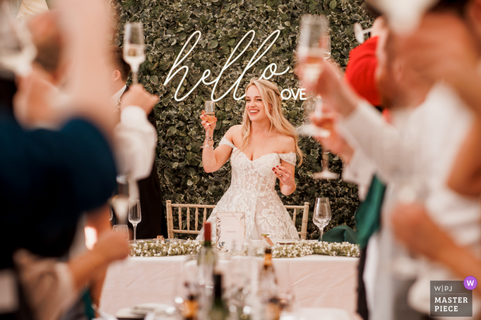 Fotografia del luogo di matrimonio della Chenies Manor House nel Buckinghamshire di Ricarica di bicchieri durante un brindisi di ricevimento