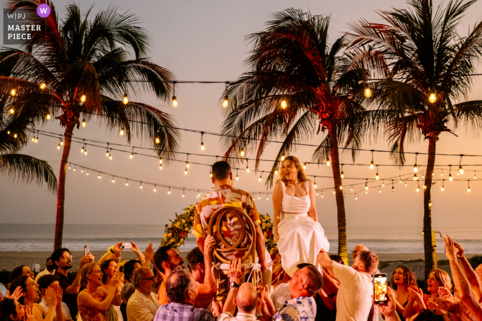 Documentary photography from a wedding venue in Puerto Escondido of bride and groom at their reception by the sea under palm trees