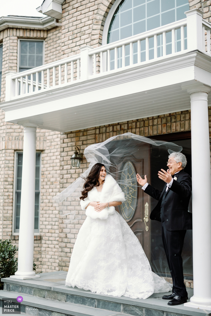 Beste Hochzeitsfotografie aus Newton, MA, aufgenommen, als die Braut und ihr Vater ihr Haus verlassen und der Wind den Schleier aufbläst