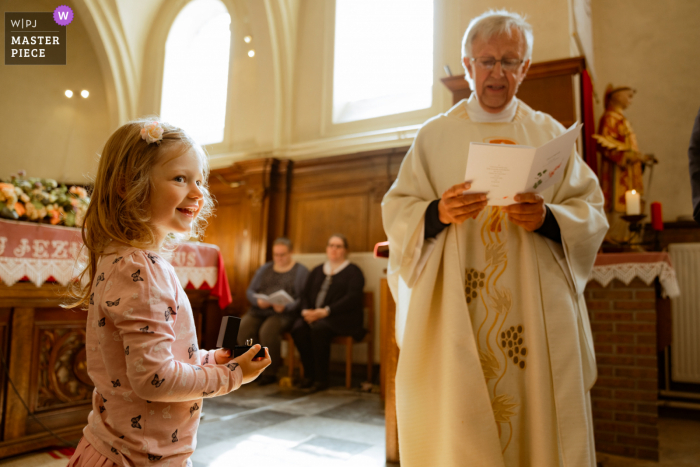 El fotógrafo de bodas de Vlaams Brabant en la iglesia de Bekkevoort capturó a una niña orgullosa en el altar con anillos