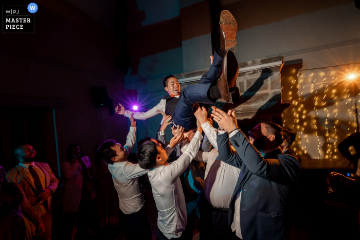 Documentary photography from Manor Vacheresses wedding venue in Nogent-le-Roi, Eure-et-Loir showing Groom during party getting tossed around