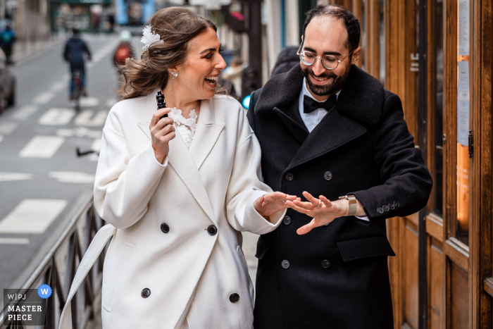 Fotografia do local do casamento em Paris mostrando os noivos rindo ao olhar para seus anéis após a cerimônia