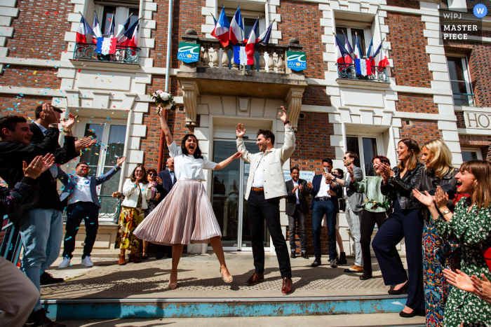 La migliore fotografia della location per matrimoni a Parigi che mostra I neo sposi festeggiano mentre escono dal municipio