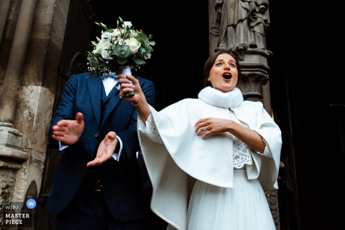 Fotografía documental de una iglesia en Francia Justo después de que la novia sale de la iglesia, oculta sin querer el rostro de su esposo con el ramo que sostiene