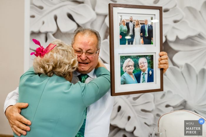 Fotografia della location del matrimonio a Madrid presso Finca Fuente che mostra la reazione dei genitori degli Grooms a un regalo con foto incorniciata