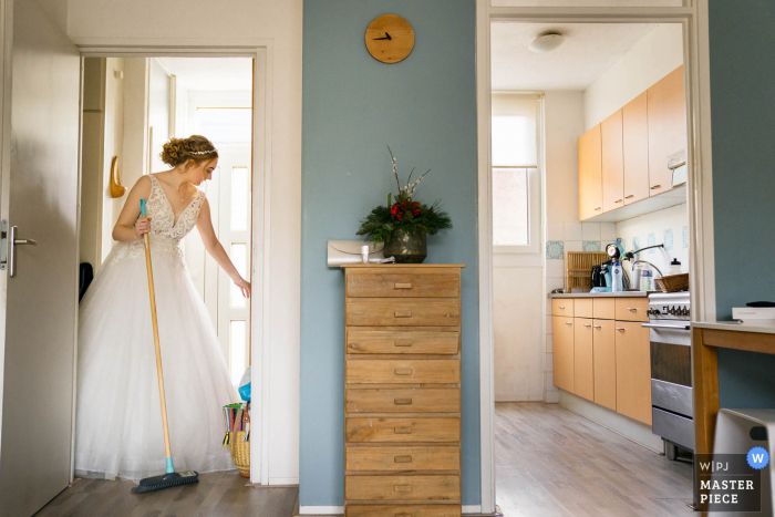 La migliore fotografia di matrimonio dai Paesi Bassi che mostra La sposa ha ancora un po' di tempo prima che lo sposo venga a prenderla, quindi ha deciso di pulire il pavimento una volta in più