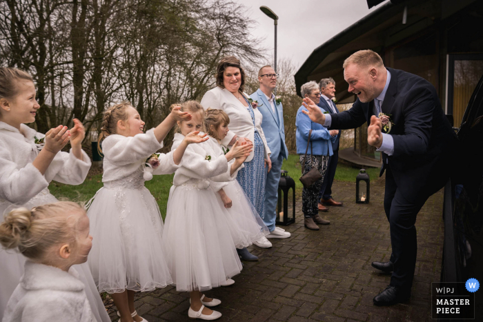 Fotógrafo de bodas documental en el lugar del evento The Waterley en Lelystad, Flevoland, Países Bajos, capturó al novio saludando a las doncellas de las novias