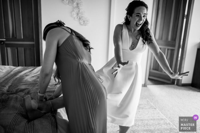 Best Fort Bragg wedding venue photography at Holly's Ocean Meadow showing A bride reacting to the entrance of someone off camera while her friend puts her shoe on her