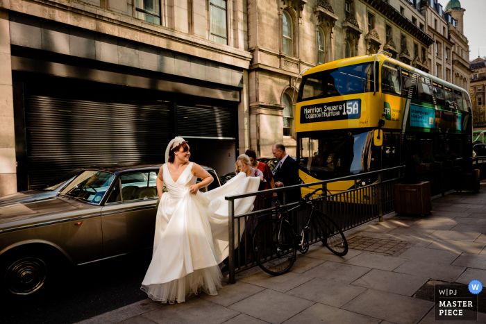 Ein dokumentarischer Hochzeitsfotograf in Dublin City hielt die Braut fest, die mit Hilfe beim Halten ihres Kleides ankam