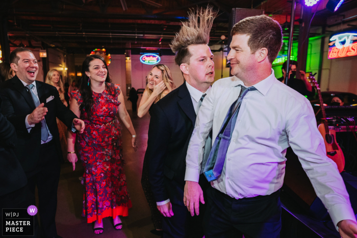 Ravenswood Event Center wedding image from a Chicago venue showing a guest lets his hair down while on the dance floor during the reception