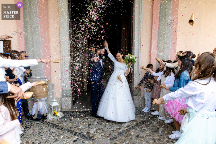 Dokumentarfotografie von einem Hochzeitsort in Verbania, Italien, von dem Konfetti, das über den Ausgang von Braut und Bräutigam geworfen wird Dokumentarfotografie von einem Hochzeitsort in Verbania, Italien, von dem Konfetti, das über den Ausgang von Braut und Bräutigam geworfen wird