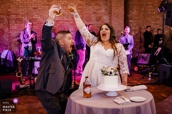 Beste Hochzeitsfotografie in Rockwell on the River in Chicago, die Braut und Bräutigam zeigt, wie sie Getränke vom Kuchentisch anstoßen