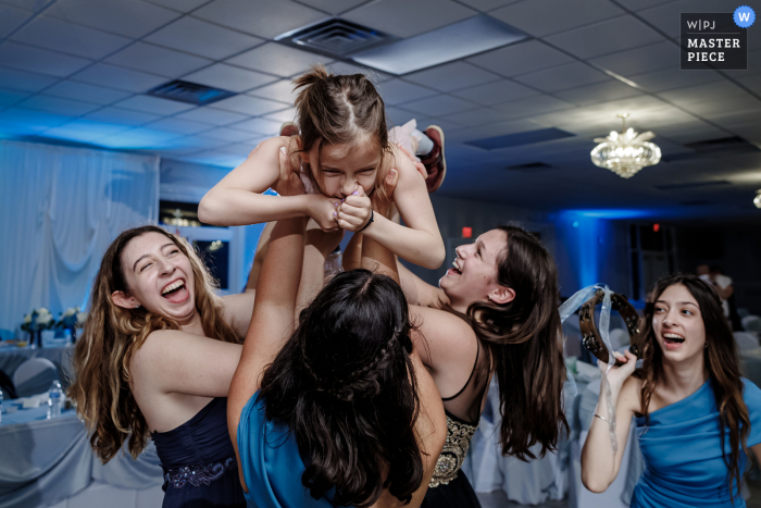 Third Lake Hochzeitsfotografie in New Gracanica von einem kleinen Mädchen, das von Frauen während eines lustigen Empfangstanzes hochgehoben wurde