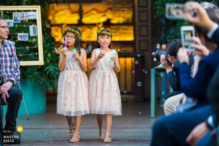 Imagen de la boda de Valentine DTLA de un lugar de Los Ángeles que muestra a las floristas haciendo burbujas y caminando por el pasillo durante la ceremonia de la boda